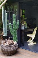 Office in back garden with log basket and fake cacti. Hackney garden London 