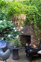 Outdoor fire place with dog statue and wooden light hanging. Hackney, London