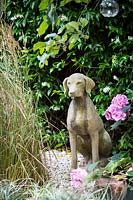 Small garden with dog statue in gravel with grasses. Hackney, London