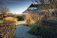 Cobbled pathways, topiary and grasses in the Courtyard Garden at Bury Court Gardens, Hampshire, UK. Designed by Piet Oudolf and John Coke.