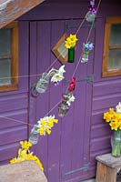 Small vases with flowers tied on string as bunting
