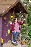 Young girl sat in front of decorated playhouse