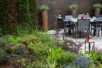 Contemporary suburban garden with copper feature wall, containers and seating area