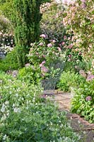 Garden seat amongst Kolkwitzia amabilis 'Pink Cloud', Rosa 'Gertrude Jekyll', Allium, Geranium and Eryngium 