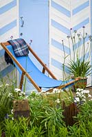 Blue deck chair with Achillea ptarmica 'The Pearl' and Verbena bonariensis. By The Sea - RHS Hampton Court Palace Flower Show 2017 - Design: James Callicott - Sponsor: Southend Borough Council.