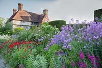 The Long Border in May with Papaver commutatum 'Ladybird', Honesty, Gladiolus, Alliums. Great Dixter, Sussex