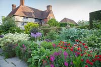 The Long Border in May with Papaver commutatum 'Ladybird', Cynara, apiaceae, Fennel, Euonymus, Honesty, Gladiolus, Alliums. Great Dixter, Sussex