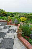The house patio with terracotta pots. Black and grey paving adds contrast.