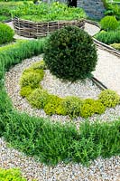 Formal garden with Taxus baccata topiary and herbs separated with gravel and woven boundary. Bridgend College: The Life of a Hermit. Designer: Matthew Joseph, RHS Cardiff Show 2017