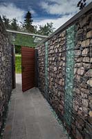 Gabion walls leading to wooden gate