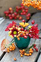 Autumnal display with Chrysanthemums in reds, yellows and oranges, rosehips and orange Pyracantha berries