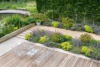 Nepeta 'Walker's Low', Alchemilla mollis, Euphorbia wulfenii, lining a gravel path next to contemporary deck and York stone patio with metal furniture in a Tom Hoblyn designed garden at Heatherbrae