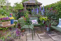 The Anneka Rice Colour Cutting Garden - Seating area with meatl chairs and bench in front of shed. Radio 2 Feel Good Gardens- RHS Chelsea Flower Show 2017 