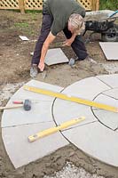Man levelling mortar as base for circular slabs of new patio
