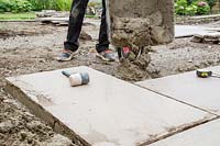 Man adding mortar to foundation of compressed crushed concrete as base for new paving
