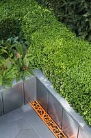 City Living - aerial view of modern grey paving with drain grates and metal raised bed with Buxus sempervirens hedge, Adiantum pedatum, Hosta 'Devon Green' and Taxus baccata boundary - RHS Chelsea Flower Show 2017