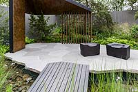 Recreation of boreal forests with angular loggia of burnt larch lined with pattinised copper and burnt timber cube seats on granite blocks paving - The Royal Bank of Canada Garden - RHS Chelsea Flower Show 2017 - Designer: Charlotte Harris - Sponsor: RBC