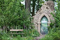 The Welcome to Yorkshire Garden - A view of the bench and the ruined sandstone abbey, surrounded by digital purpurea, leucanthemum vulgare, meadow cranesbill and many wild herbs and flowers -RHS Chelsea Flower Show