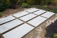 Making a mixed material patio - grid of large porcelain slabs ready to infill with granite setts