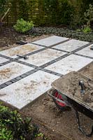 Making a mixed material patio - patio with grid of large porcelain slabs infilled with granite setts - contrasting colours 