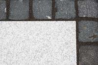 Making a mixed material patio - detail of paving where large porcelain slabs are mixed with granite setts

