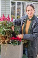 Woman adding compost to fill in between plants in Winter interest container