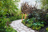 Pathway of smooth slabs separeted with gravel in wild garden. The Zoflora and Caudwell Children's Wild Garden - RHS Hampton Court Palace Flower Show 2017
