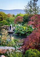Japanese style garden with Acer palmatum, Zantedeschia aethiopica, Rodgersia aesculifolia and Gunnera manicata surrounding pond, sculpture by Matthew Maddocks - 'At One With...A Meditation Garden' - Howle Hill Nursery, RHS Malvern Spring Festival 2017