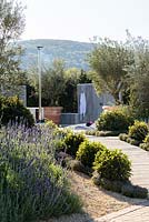 Patio with outdoor kitchen, heated pool and  seating area surrounded by olive trees in large terracotta planter - The Retreat, RHS Malvern Spring Festival 2017 