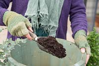 Woman adding compost to empty container