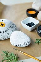 Making a stone owl decoration - once the white base paint is dry, paint little black feather marks on the body of the owl