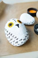 Making a stone owl decoration - paint on a beak and a large pair of eyes in orange paint
