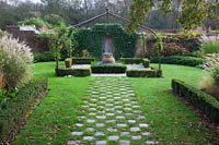 Grass and stone setts form a chequered path to pergola covered small Buxus - box edged, Lavender filled  knot garden with terracotta urn - Brightling Down Farm