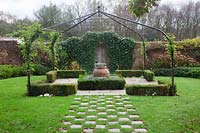 Grass and stone setts form a chequered path to pergola covered small Buxus - box edged, Lavender filled knot garden with terracotta urn - Brightling Down Farm
