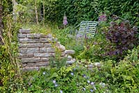 Shade planting with Rose, ferns, Astrantia and Geranium next to stone wall - BBC Gardener's World Live, Birmingham 2017 -Wyevale Garden Centres: Romance in the Ruins designed by Claudia de Yong