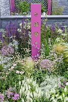 Bug hotel and planting in pink, blue and white with Salvia, Stipa and Allium with slate wall  - BBC Gardener's World Live, Birmingham 2017 - The Lanwarne Landscapes 'Contemporary Bee and Butterfly' Garden - Head Sponsors: IntoUniversity, Big City Bright Future Programme, Black Rock - Best Landscape Construction. Best Construction Landscaper