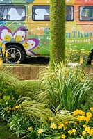 Colourful hippie van with planting of Hakonechloa, yellow Daylilies and Coreopsis in BBC Gardener's World Live, Birmingham 2017 - GreenThumb's 'With a Twist' Garden - Designer: Pip Probert