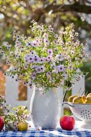 Jug of asters and harvest on table, October.