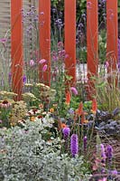 Kniphofia 'Royal Standard', Achillea 'Anthea' and Sanguisorba hakusanensis with orange painted fence in the 'Facing Fear, Finding Hope' Garden at Tatton RHS Flower Show 2017