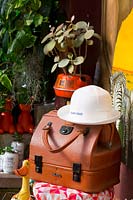Old brown leather lawn bowls bag with a white ladies lawn bowls hat on a vintage stool.