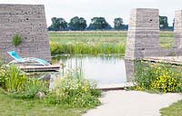 A swimming pond with towers made of recycled paving tiles near a concrete jetty