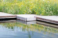 A swimming pond with jetty made of recycled wood and concrete.