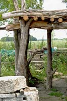 Recycled roof shelter made from treetrunks and braided willows.