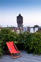 Deckchair on terrace with view of city of Milan and Velasca tower. Italy, May. 