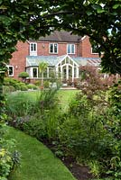 Glimpse of the Renwick's modern home, seen through an arch cut into a hornbeam hedge.