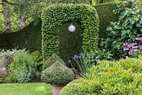 A hornbeam arch straddles a path leading to a hidden part of the garden.