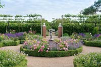 A formal box edged, sunken rose parterre. Central bed of Rosa 'Louise Odier' and catmint. Outer beds of Roses, Salvias, Astrantias and Geranium 'Blue Cloud'. Pleached crab apple trees contain space.