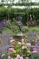 A cherub fountain, rising above Catmint and Roses.