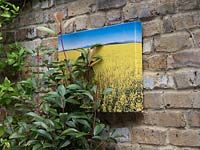 Countryside scene canvas hanging on brick wall.