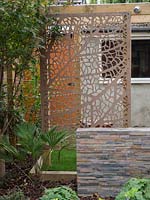 Cut metal screen adds depth to small garden still keeping it light and airy